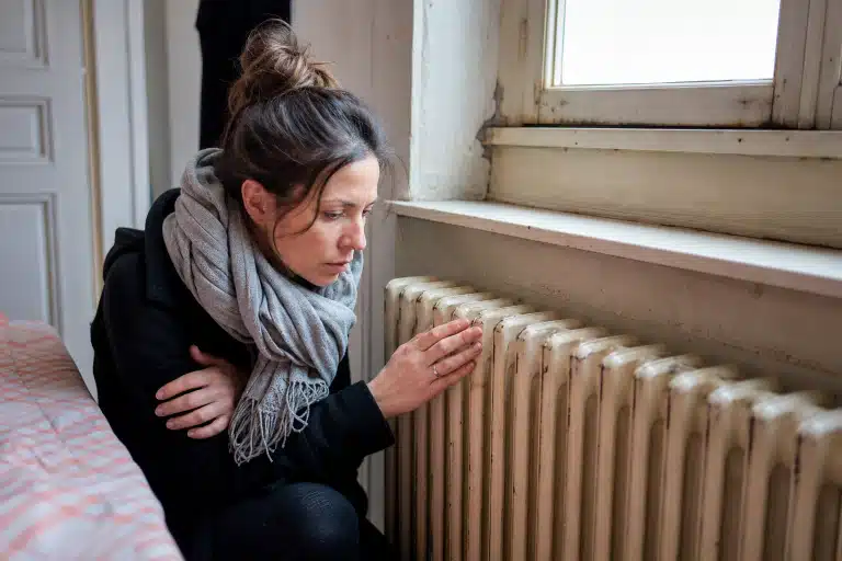 Femme examinant un radiateur près d'une fenêtre